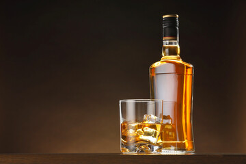 Whiskey with ice cubes in glass and bottle on table, space for text - 757613080