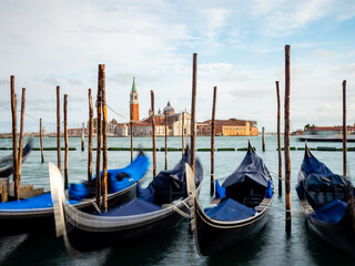 Fototapeta na wymiar Gondolas moored by Saint Mark square with San Giorgio di Maggiore church in Venice, Italy