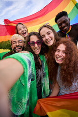 Fototapeta premium A crowd of happy people in colorful smile for a vertical selfie with a rainbow flag, capturing their fun and leisurely recreation. Gay and lesbian friends together in the gay pride parade LGBT concept