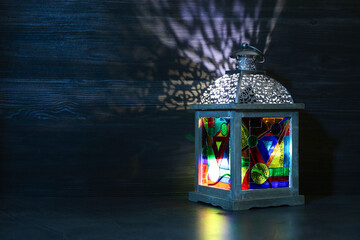 Decorative Arabic lantern on table against dark background. Space for text