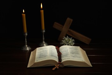 Crosses, rosary beads, Bible and church candles on wooden table