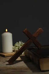 Cross, Bible, church candle and flowers on wooden table