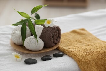 Fototapeta na wymiar Spa stones, flowers and herbal bags on towel indoors