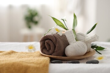 Fototapeta na wymiar Spa stones, flowers and herbal bags on towel indoors