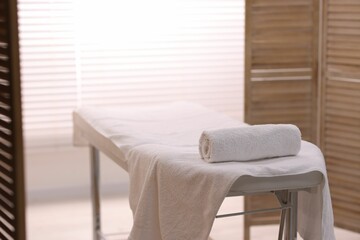 Rolled towel on massage table in spa center