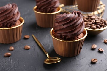 Delicious chocolate cupcakes and coffee beans on black textured table, closeup