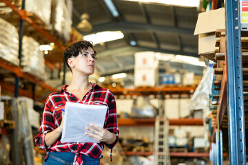 Latin woman making stock control, verifying documents while working warehouse.