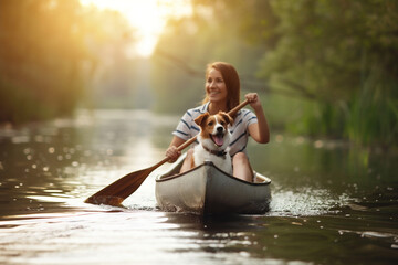 Woman rowing on canoe with her pet dog across the lake. Summer activities and water sports. Selective focus. - obrazy, fototapety, plakaty