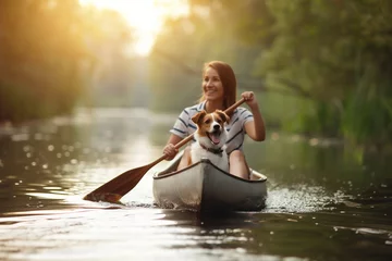 Foto op Canvas Woman rowing on canoe with her pet dog across the lake. Summer activities and water sports. Selective focus. © elinorka