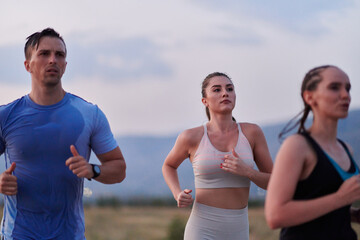 A diverse group of runners trains together at sunset.