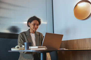 TV presenter using laptop at table in building event, with fun display device