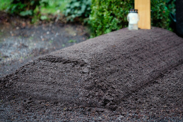 fresh grave in a cemetery with mounded earth without flowers and decorations