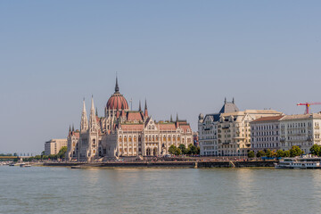 View of the Hungarian Parliament Building beside the Danube River on a sunny day in Budapest, Hungary