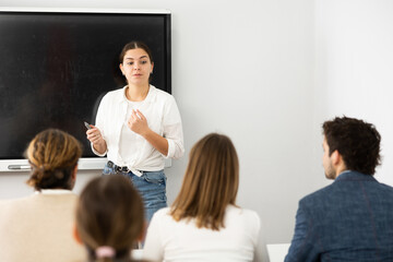Young female teacher giving lecture to group of student