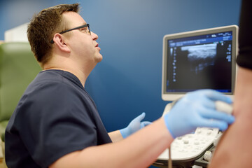 Professional vascular surgeon making ultrasound of the vein of patient in clinic before vein...