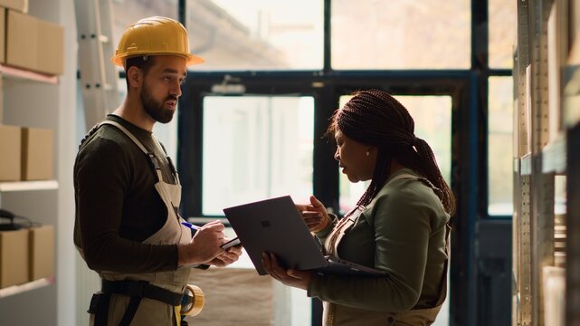 Chief operations officer and worker perform warehouse inventory controls, keeping quality standards high. Skilled experts in storage establishment prepare to ship parcels, crosschecking delivery info