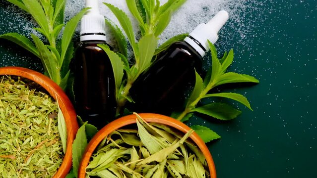 Stevia rebaudiana.Dry, liquid and powder stevia on a dark green background.Stevia extract liquid and stevia powder with green leaves.Vegetable sweetener. 4k footage