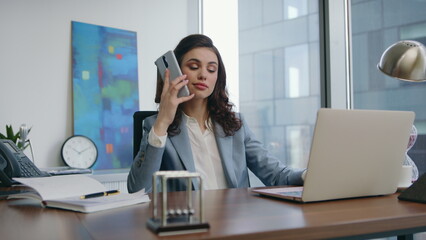Successful businesswoman talking telephone sitting at desk with laptop close up.
