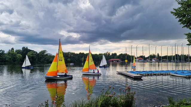 Sailboats glide on cloudy lake, against natural landscape backdrop Maschsee Hanover Germany