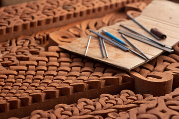 Horizontal photo. Set of work tools, gravers, chisels lies on red brick religious slab with pattern...