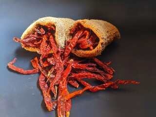 Dried chilies put in a burlap sack on a black background