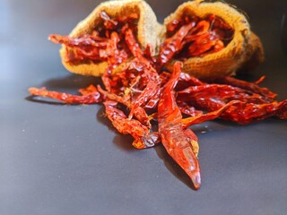 Dried chilies put in a burlap sack on a black background