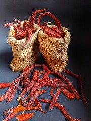 Dried chilies put in a burlap sack on a black background