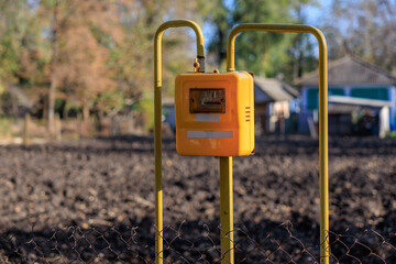 A yellow meter is on a pole in a field