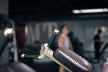 A person working out in the background is obscured behind the gym equipment