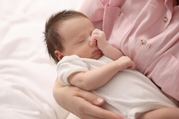 Mother with her sleeping newborn baby on bed, closeup