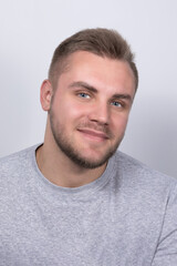 Obraz premium A smiling young blond man with a beard wearing a gray shirt