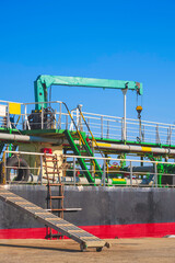 Oil pipeline system with crane machinery in tanker ship during maintenance and renovation work in shipyard area at harbor, side view and vertical frame