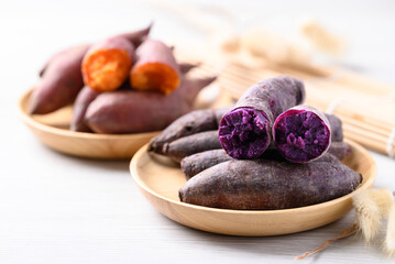 Boiled purple and orange sweet potato on wooden plate