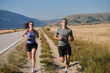 Energized by the beauty of nature, a couple powers through their morning run, their bodies and...