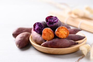 Boiled purple and orange sweet potato on wooden plate