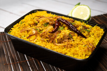 Achari chicken khichuri biryani rice pulao with cucumber and lemon slice served in dish isolated on wooden table side view of bangladeshi and indian spicy lunch food
