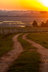 rural dirt road with irrigated rice fields in the background and a beautiful sunset in Brazil