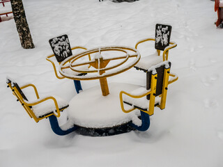 The playground in the courtyard of a residential building is buried under a large layer of snow, winter weather, snowfall