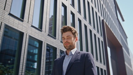 Smiling entrepreneur walking urban business area sunny morning in suit close up.