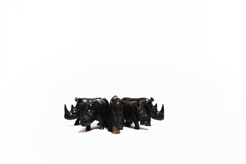 Herd of rhinos made of ebony wood in white background.