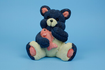 Blue ceramic teddy bear holding a pink fish in blue background.