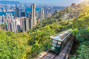 The famous green tram on the slope of Victoria Peak in Hong Kong passes, lifting visitors to the...