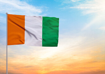 3D illustration of a Ivory Coast flag extended on a flagpole and in the background a beautiful sky with a sunset