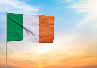 3D illustration of a Ireland flag extended on a flagpole and in the background a beautiful sky with a sunset