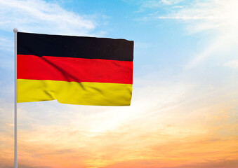 3D illustration of a Germany flag extended on a flagpole and in the background a beautiful sky with a sunset