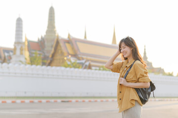 Traveler asian woman in her 30s, backpack slung over her shoulder, explores the intricate details...