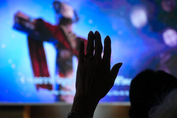 Silhouette Hand Raising Worshipper, blurred christian cross background