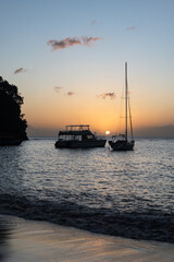 Two silhouetted boats are moored near the shore, as the sunsets in the warm Winter weather of the...