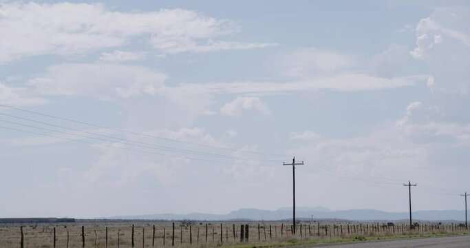 Train passing in the distance with telephone poles in the foreground, surrounded by endless Texas skies