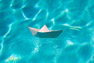 White paper boat, origami paper ship into the clear sea water.